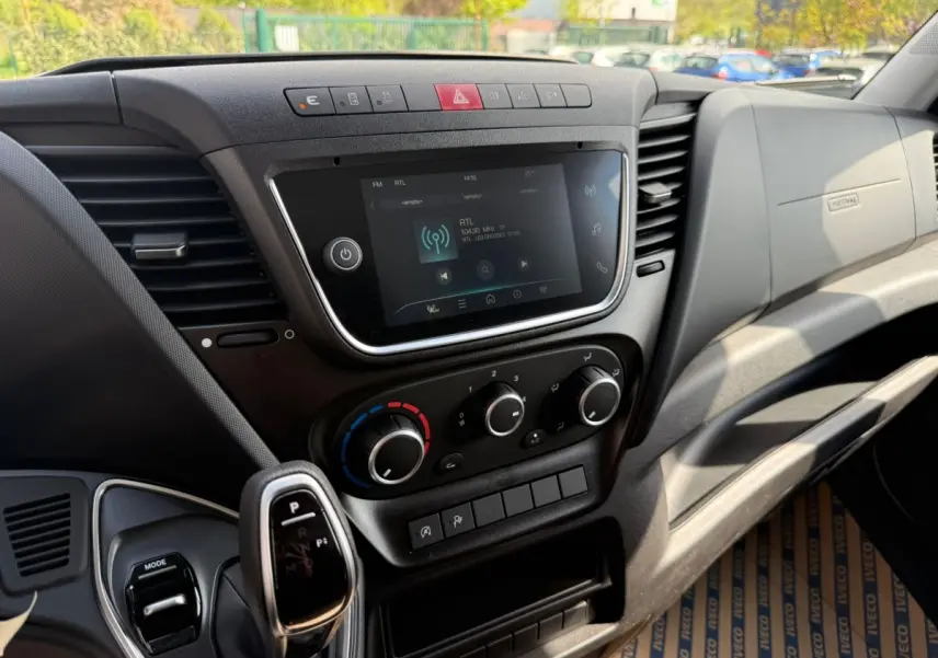 Vue intérieure du tableau de bord de l'Iveco Daily 2026, avec écran tactile, commandes climatisation et levier de boîte automatique.