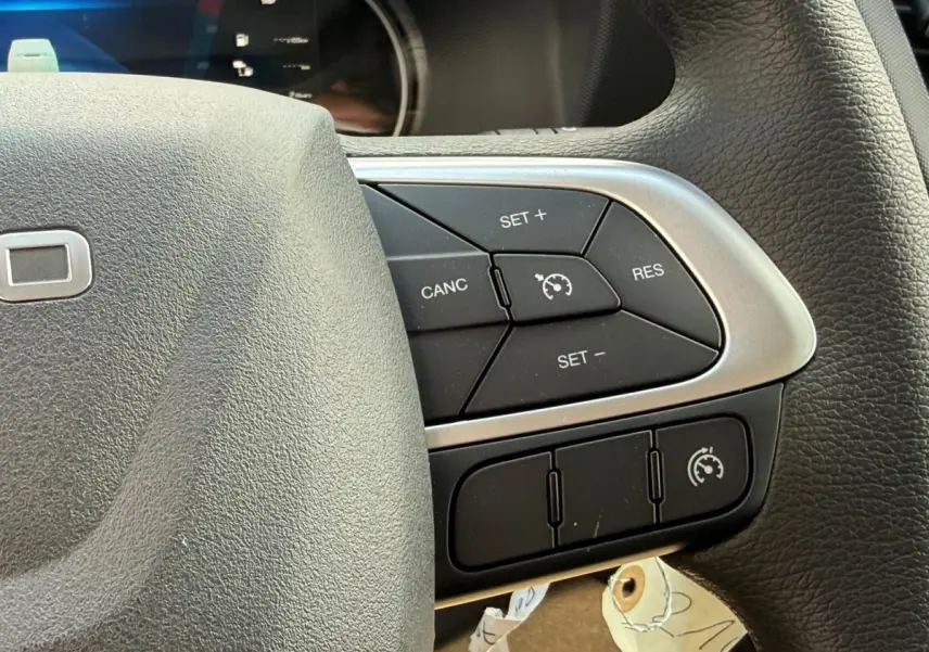 Gros plan sur les commandes de régulateur de vitesse au volant noir du Iveco Daily blanc 2026, côté droit.