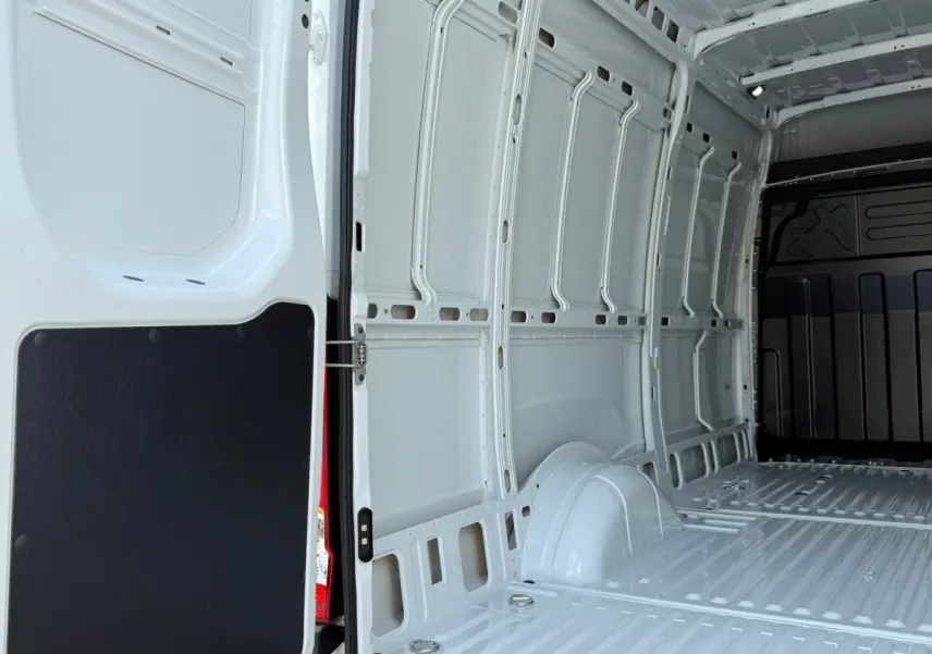 Vue intérieure arrière du fourgon Iveco Daily blanc, montrant l'espace de chargement vide et les parois métalliques.