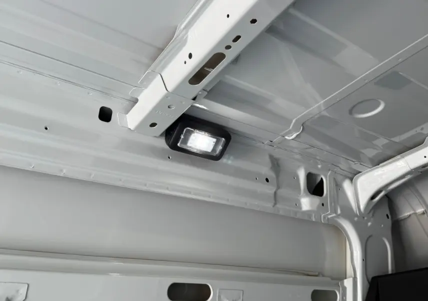 Vue intérieure du plafond blanc du fourgon Iveco Daily 2026, mettant en valeur une lampe LED intégrée.