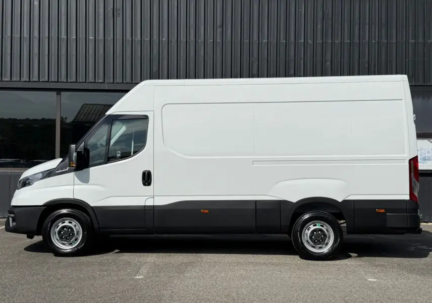 Fourgon Iveco Daily blanc vu de profil côté gauche, avec bas de caisse noir et grande surface lisse sans fenêtres.