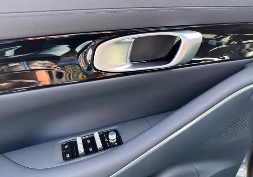 Détail de la poignée intérieure et des commandes de fenêtre côté conducteur du Geely E5 gris foncé 2026.