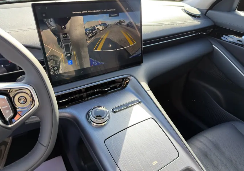 Vue intérieure du tableau de bord et console centrale du Geely E5 gris foncé, avec écran tactile affichant la caméra de recul.
