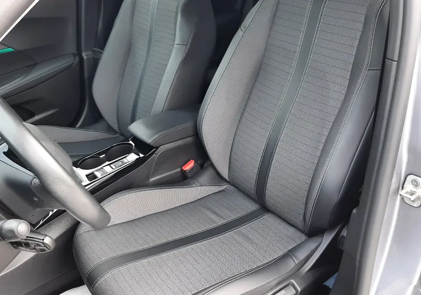 Intérieur du Peugeot 2008 gris 2021, vue rapprochée des sièges avant en tissu gris et cuir noir avec coutures contrastées.
