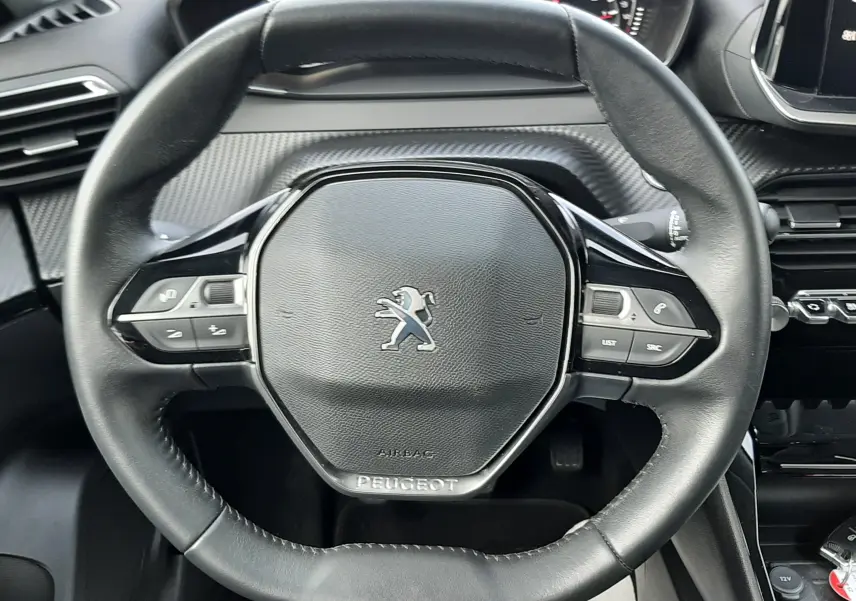 Vue rapprochée du volant cuir noir du Peugeot 2008 gris 1.5 BlueHDi 110 Allure avec commandes intégrées.
