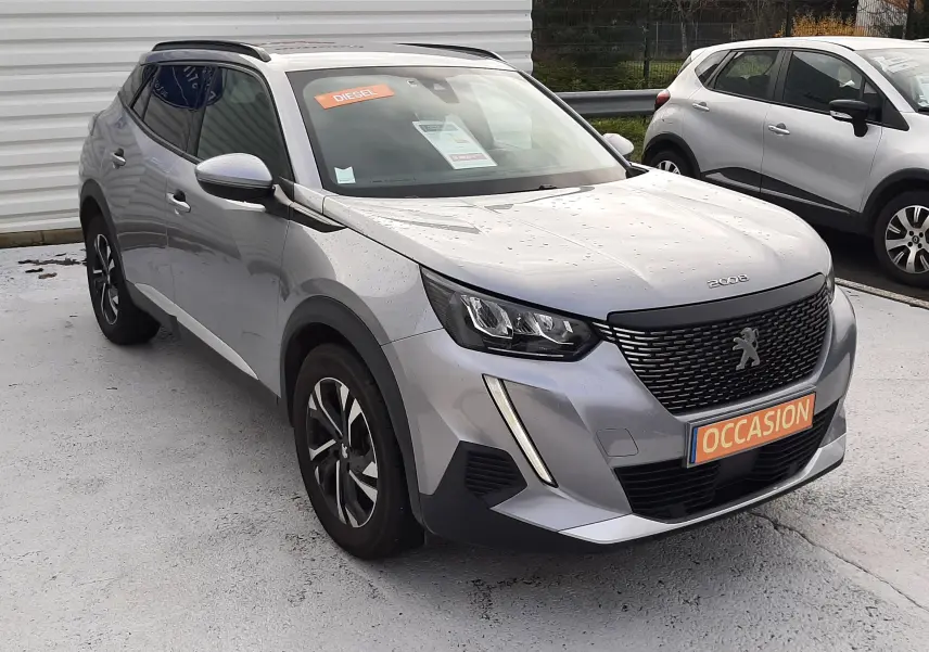 Peugeot 2008 gris en 3/4 avant droit, avec calandre noire et plaque "OCCASION" visible sur un parking extérieur.