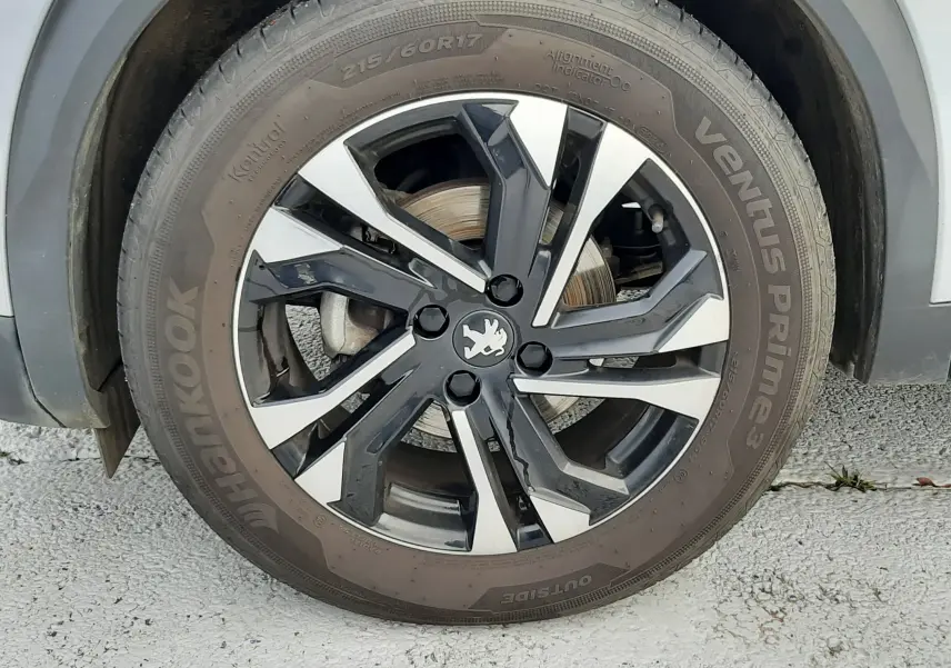 Gros plan sur la roue avant gauche gris clair d'un Peugeot 2008 1.5 BlueHDi 110 Allure avec jante alliage bicolore.