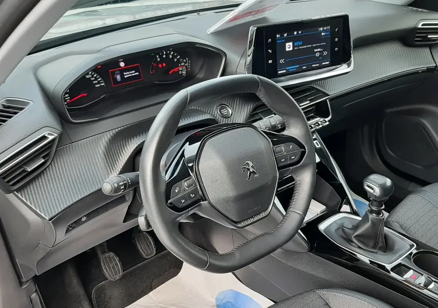 Vue intérieure côté conducteur du Peugeot 2008 gris 2021, avec volant compact, tableau de bord numérique et levier de vitesses manuel.
