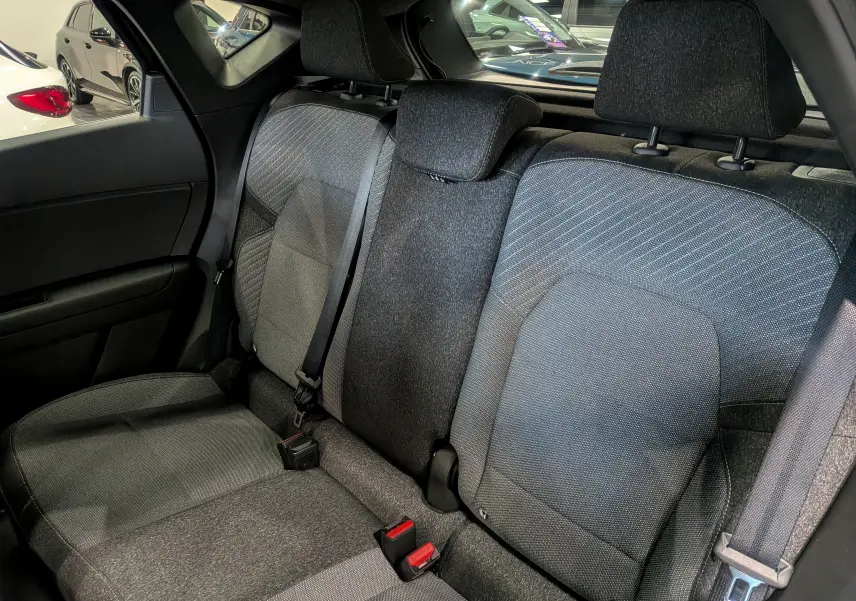 Vue intérieure sur les sièges arrière en tissu gris du Renault Captur Mild Hybrid 2025, avec ceintures et appuie-têtes visibles.