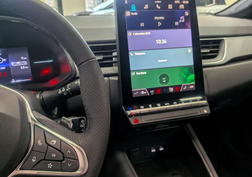 Intérieur du Renault Captur 2025, vue sur le volant noir et l'écran tactile central affichant l'interface multimédia.