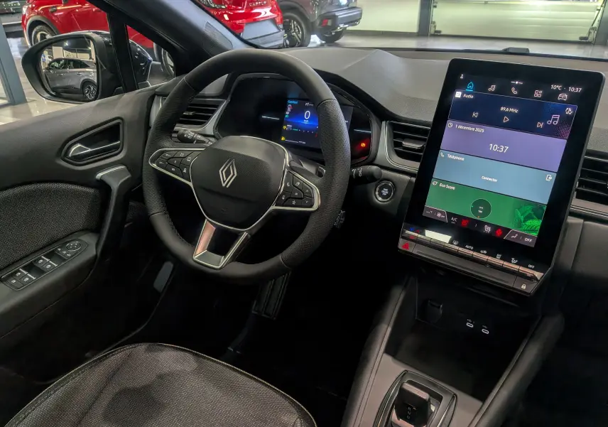 Vue intérieure côté conducteur du Renault Captur 2025 noir, avec volant multifonction et écran tactile vertical lumineux.