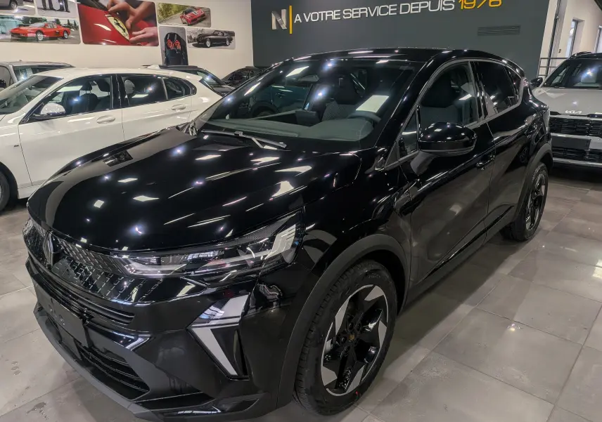 Renault Captur 2025 noir en 3/4 avant droit dans un showroom, avec jantes bi-ton et phares LED distinctifs.