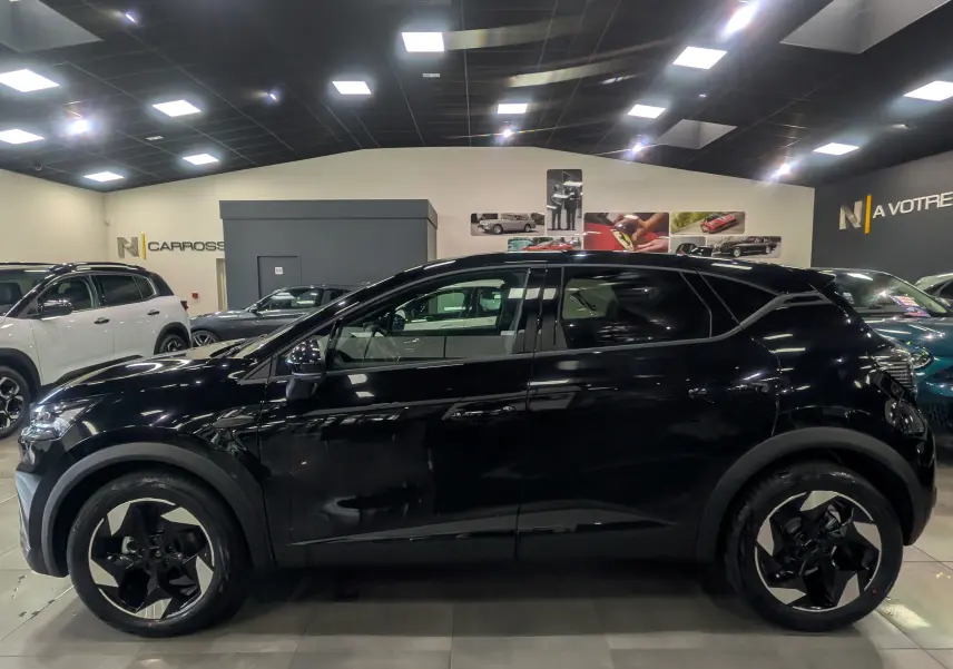 Profil côté gauche du Renault Captur noir 2025 Mild Hybrid exposé en showroom avec jantes bi-ton distinctives.