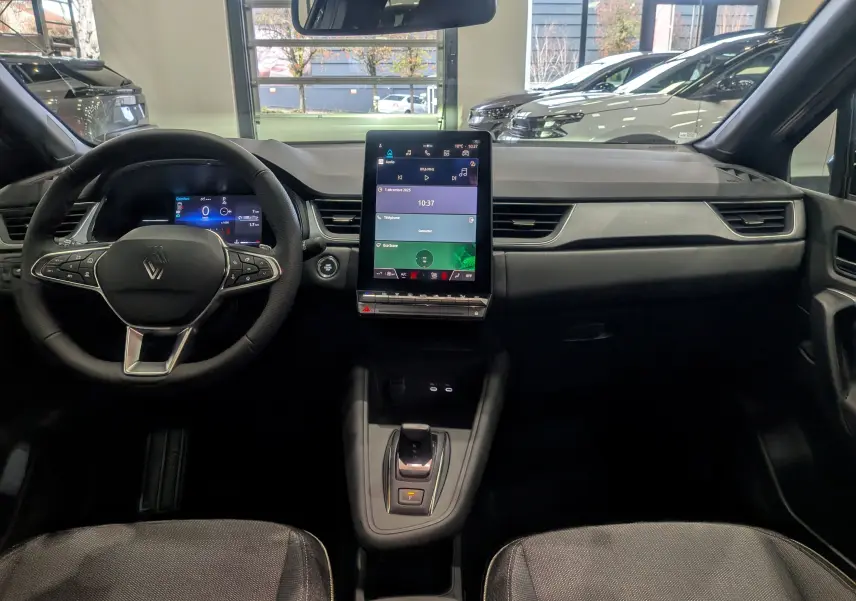 Intérieur du Renault Captur 2025 noir, vue frontale du tableau de bord avec écran tactile vertical et volant multifonction.
