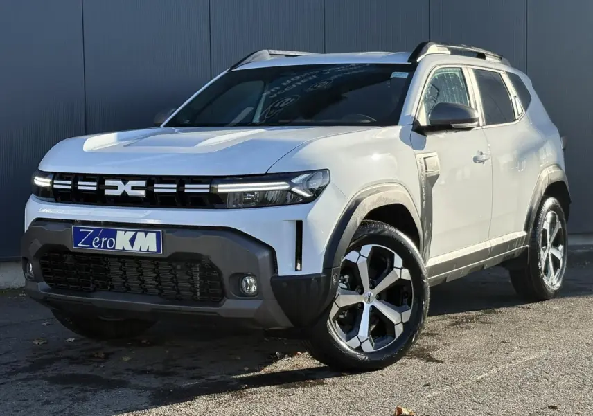 Dacia Duster blanc glacier en 3/4 avant droit, avec jantes alliage noires et grises et barres de toit noires.