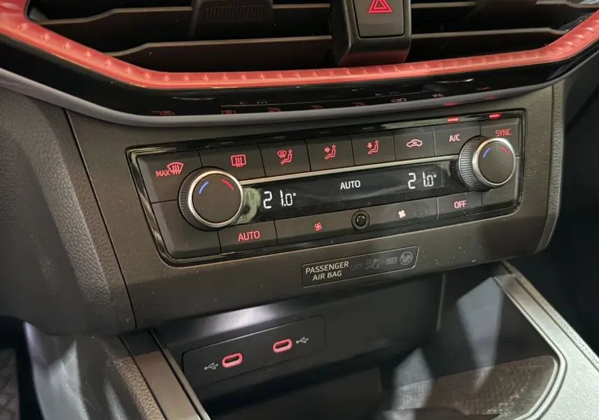 Gros plan sur la commande de climatisation digitale et ports USB rouges du tableau de bord noir de la SEAT Ibiza 2024.