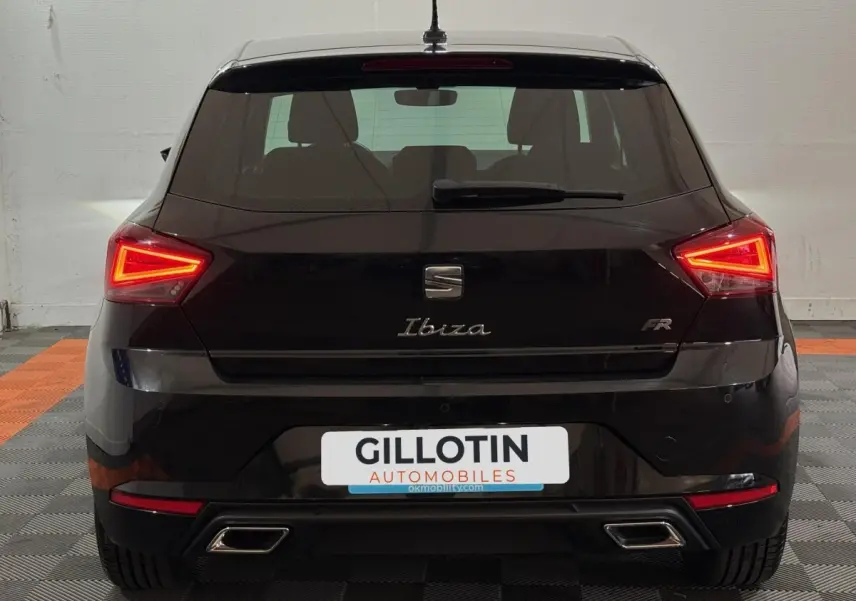 Vue arrière d'une SEAT Ibiza 1.0 TSI 110 FR noire avec feux LED triangulaires et double sortie d'échappement chromée.
