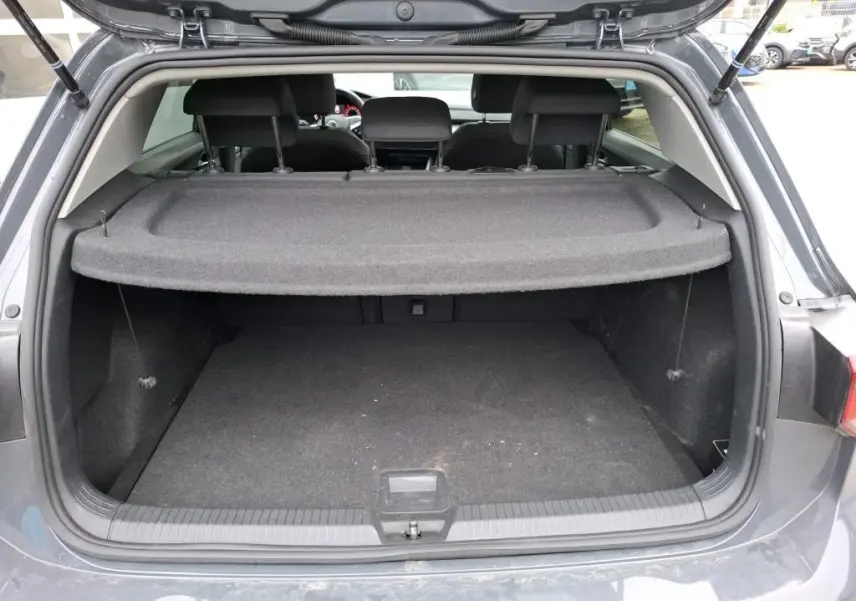 Vue arrière du coffre ouvert d'une Volkswagen Golf gris 2022, avec cache-bagages et intérieur noir visible.