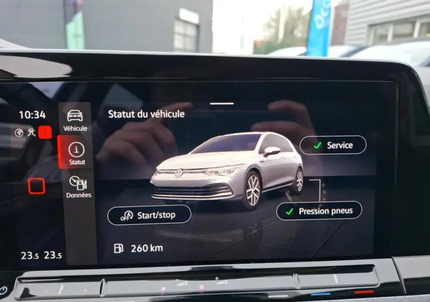 Écran intérieur affichant le statut d’un Volkswagen Golf gris en vue 3/4 avant avec alertes service et pression pneus validées.