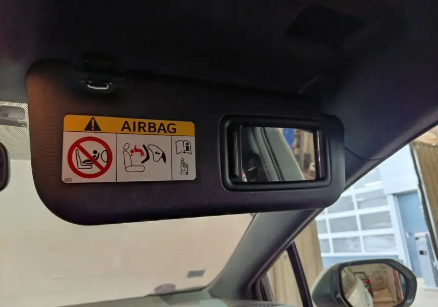 Détail du pare-soleil côté conducteur avec miroir et étiquette airbag dans une Toyota Corolla blanche 2020.