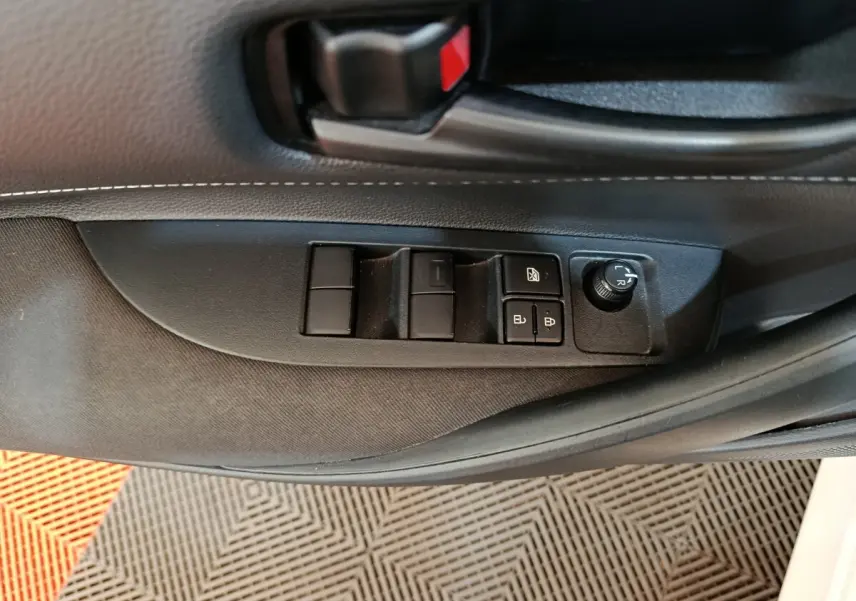 Gros plan sur la commande des vitres et rétroviseurs côté conducteur de la Toyota Corolla hybride blanche 2020.