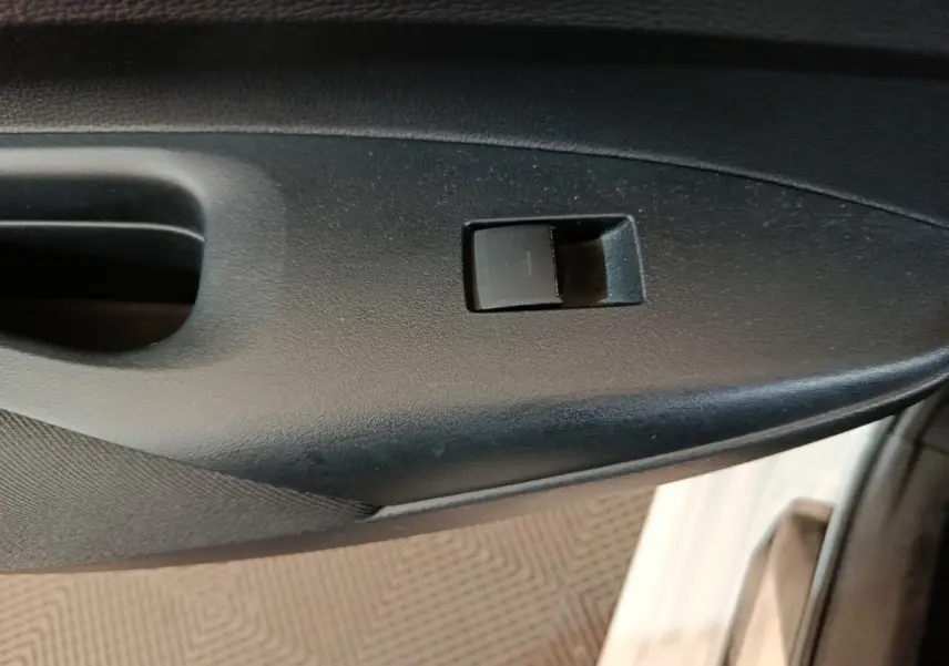 Gros plan sur la commande de lève-vitre côté droit d’une Toyota Corolla hybride blanche, intérieur noir.