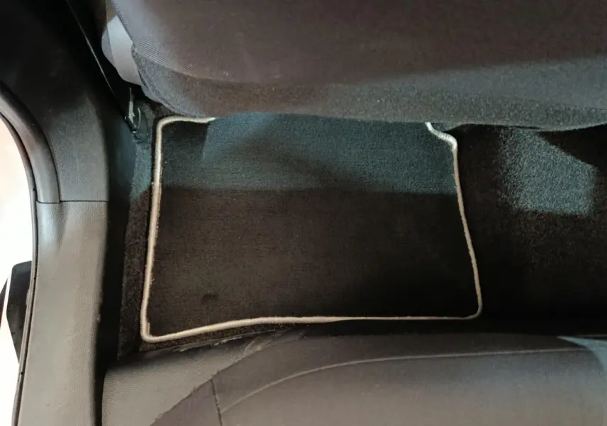 Vue rapprochée du tapis de sol noir avec bordure claire à l'arrière côté droit d'une Toyota Corolla Hybride blanche 2020.