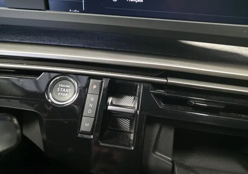Gros plan sur la console centrale noire laquée du Peugeot 3008 Hybrid 2025 avec bouton start/stop et commandes de boîte auto.