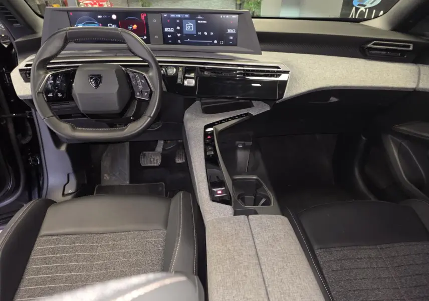 Vue intérieure avant du Peugeot 3008 2025 noir, avec tableau de bord numérique et console centrale en tissu gris.
