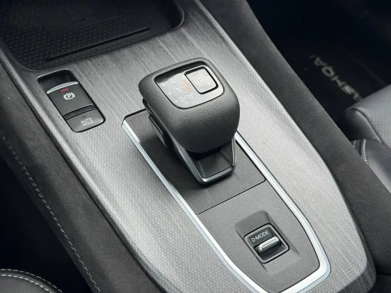 Gros plan sur la commande de boîte automatique noire et gris métallisé du Nissan Qashqai 1.3 Mild Hybrid 2024, intérieur cuir.