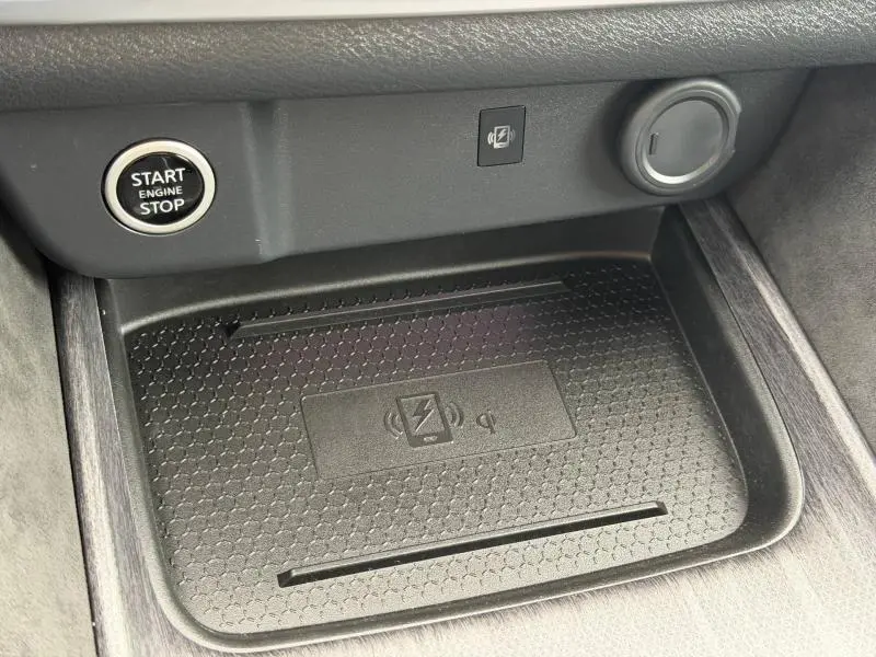 Gros plan sur le compartiment de recharge sans fil noir dans l'habitacle du Nissan Qashqai 2024, avec bouton start/stop visible.