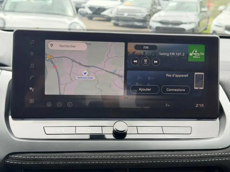 Écran tactile central du Nissan Qashqai 2024 affichant GPS et radio FM, avec commandes physiques en dessous.