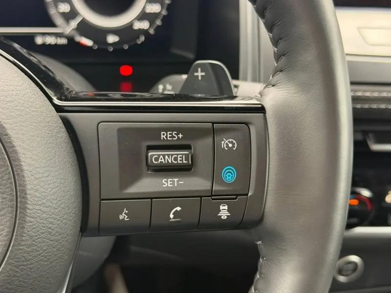 Gros plan sur les commandes du régulateur de vitesse au volant cuir noir du Nissan Qashqai 2024.
