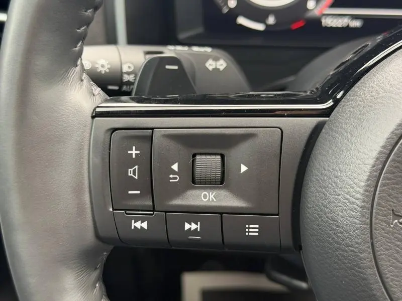 Gros plan sur les commandes multifonctions noires à gauche du volant cuir du Nissan Qashqai 2024 Noir Kuro Métallisé.