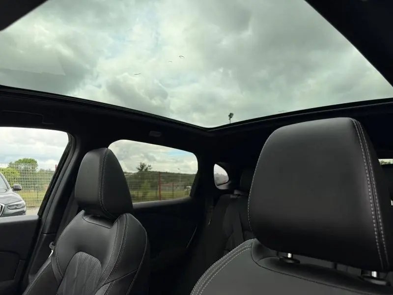 Vue intérieure du Nissan Qashqai 2024 noir Kuro, mettant en valeur les sièges cuir et le toit panoramique en verre.