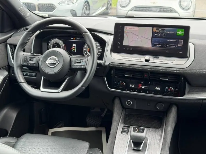 Vue intérieure du tableau de bord du Nissan Qashqai 2024 noir, avec écran tactile central et volant multifonction en cuir.