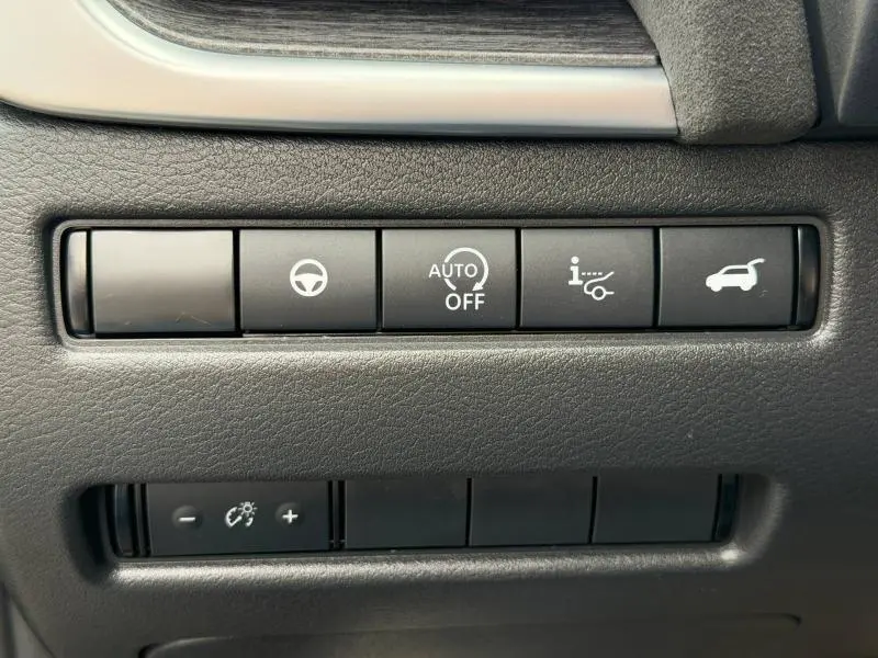 Gros plan sur les boutons de commande noirs du tableau de bord du Nissan Qashqai 2024, avec icônes blanches.