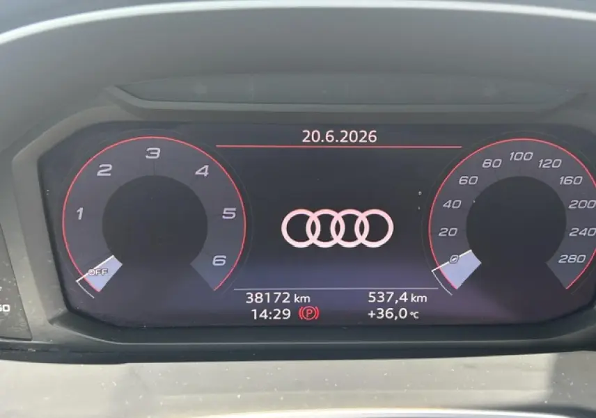 Combiné d'instruments numérique Audi Q3 blanc, affichant logo Audi, vitesse et compte-tours en rouge, vue de face.