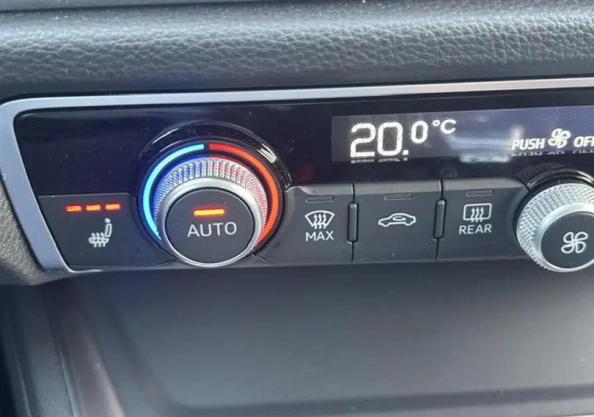 Gros plan sur la commande de climatisation automatique avec réglage à 20°C et siège chauffant activé, intérieur noir.