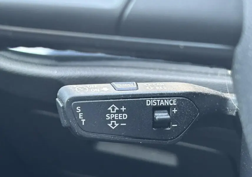 Gros plan sur la commande de régulateur de vitesse noire dans l’habitacle d’un Audi Q3 blanc de 2022.