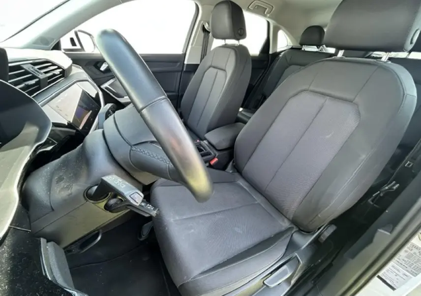 Vue intérieure côté conducteur de l'Audi Q3 Sportback 2022, sièges tissu gris et volant cuir noir.