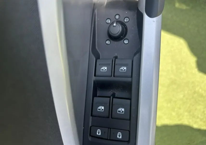 Gros plan sur les commandes des vitres et rétroviseurs côté conducteur d’un Audi Q3 blanc 2022.