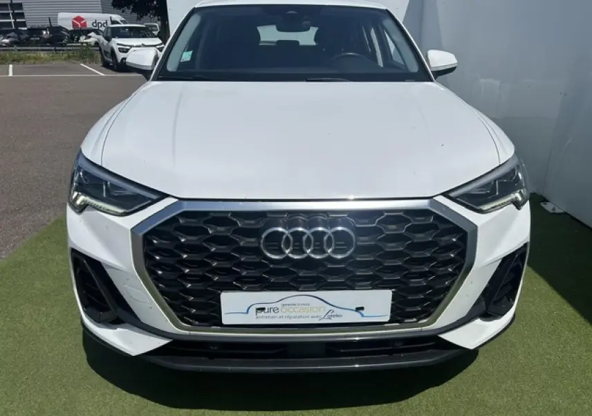 Vue avant d'un Audi Q3 blanc avec calandre noire hexagonale et phares LED distinctifs.