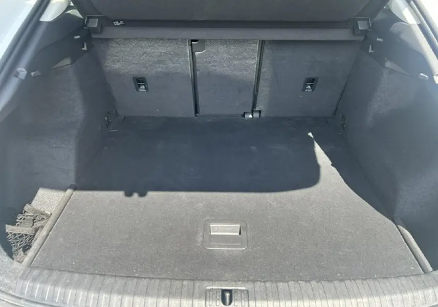 Coffre ouvert vu de l'arrière d'un Audi Q3 blanc, montrant un espace de chargement vide et tapis noir.