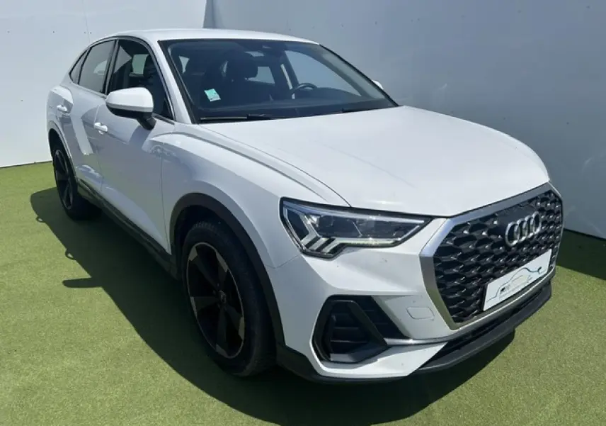 Audi Q3 Sportback blanc en 3/4 avant droit, avec calandre grenue noire et jantes aluminium noires 5 branches doubles.
