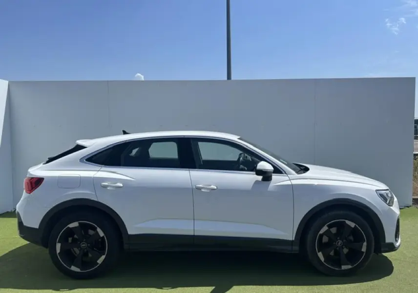 Audi Q3 Sportback blanc vue de profil côté gauche, avec jantes noires et toit plongeant distinctif.