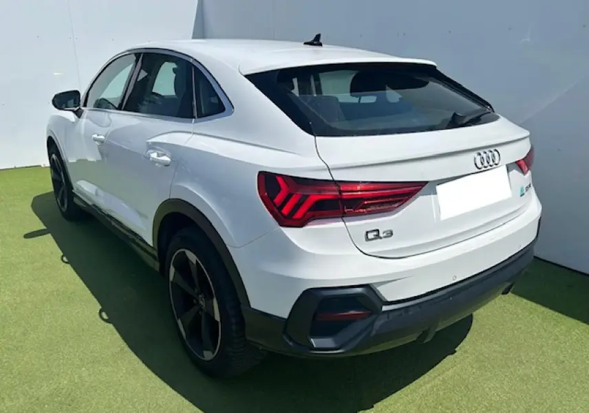 Audi Q3 Sportback blanc en 3/4 arrière droit, avec feux LED et jantes noires distinctives.