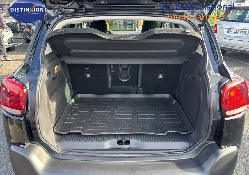 Coffre ouvert vu de l'arrière d'un Citroën C3 Aircross noir Perla Metal avec tapis de coffre marqué du modèle.