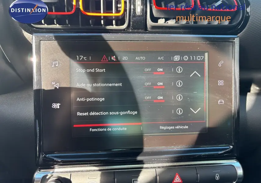 Vue rapprochée de l’écran tactile central et des aérateurs colorés rouge et orange du tableau de bord d’une Citroën C3 Aircross noir perla metal.