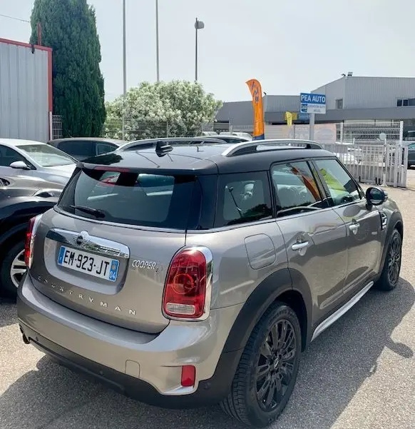 Vue 3/4 arrière droite d'une MINI Countryman Cooper D 150ch gris avec toit noir et jantes noires, stationnée en extérieur.